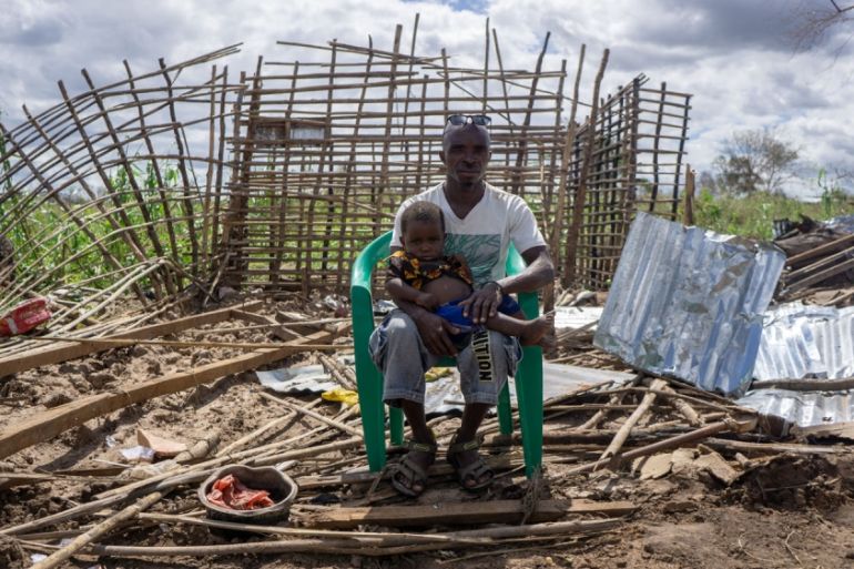 Louis Jose Batista sits with his son outside their home in Zone Seta, Macomia, demolished by Cyclone Kenneth which swept through Macomia district in northern Mozambique.