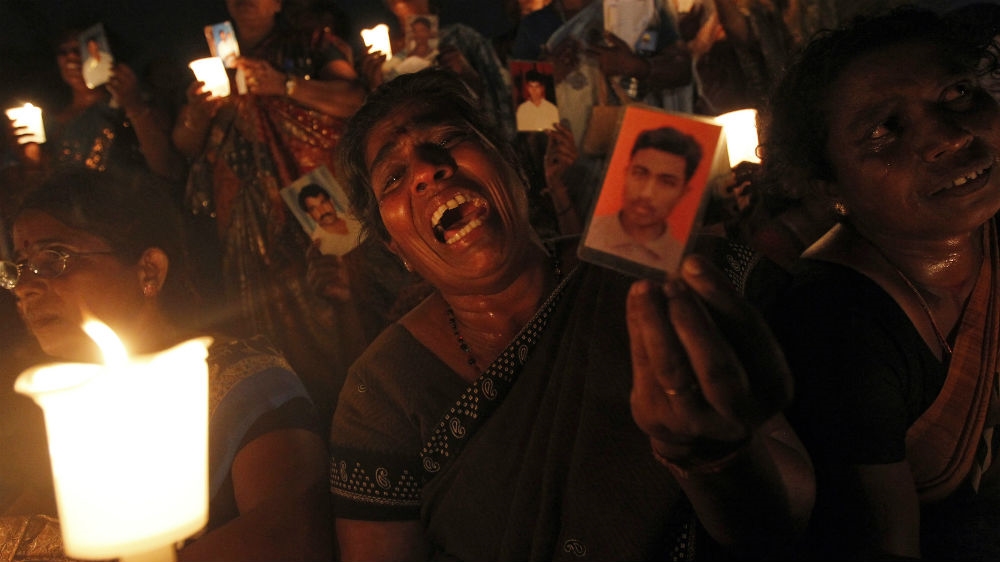 A Tamil woman holds up a picture of a family member who disappeared during the war at a vigil to mark the international day of the disappeared [File: Dinuka Liyanawatte/Reuters]