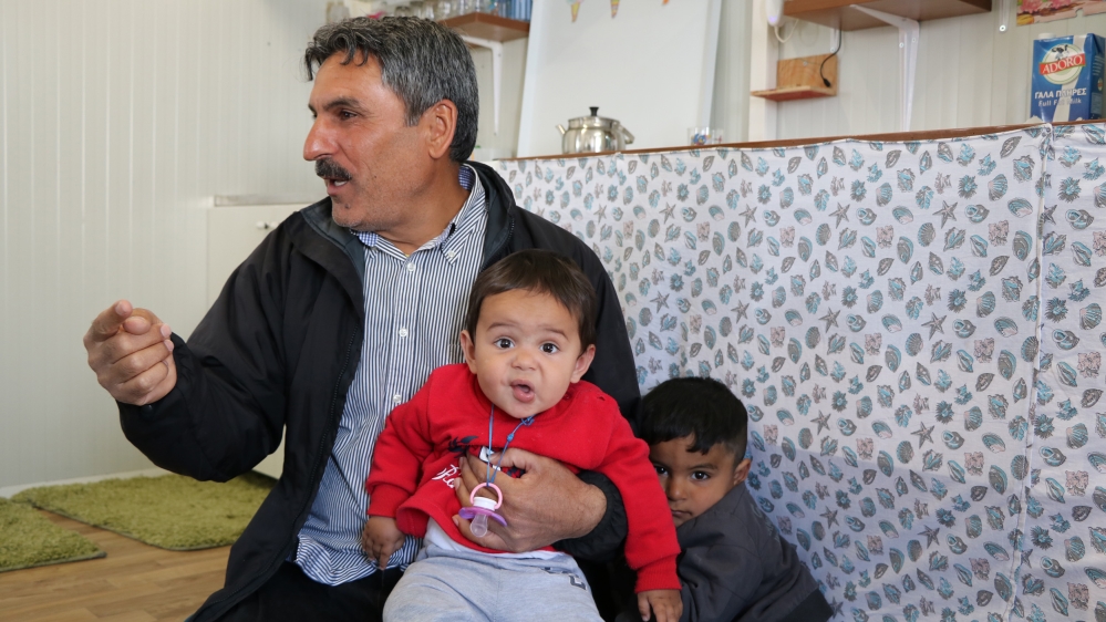 Mustafa Ibrahim, a water hole borer from the Syrian Kurdish city of Kobani, in his container home with his sons Moussa and Rahaf [John Psaropoulos/Al Jazeera]