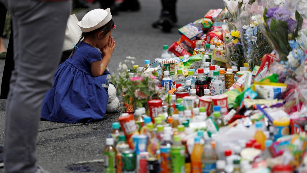 A girl prays to mourn victims as she offers flowers at the site where a stabbing occured in Kawasaki