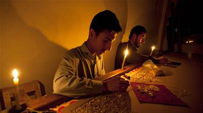 Pakistani craftsmen work by candle light during a power outage