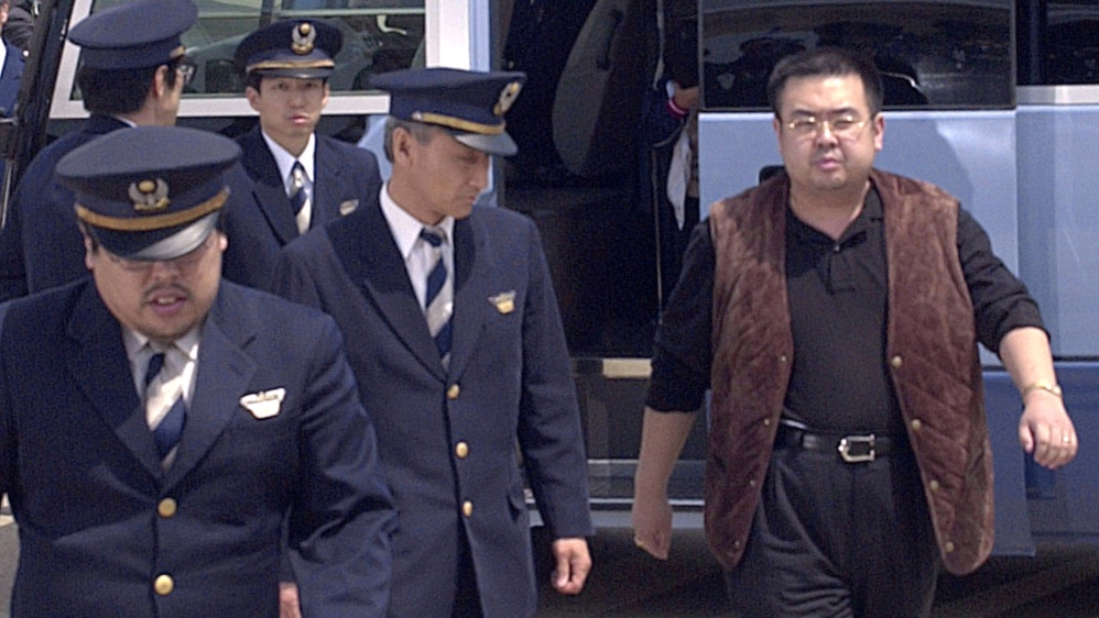 A man believed to be Kim Jong Nam, right, is escorted by police as he boards a plane upon his deportation from Japan at Tokyo's Narita International Airport [File: Kyodo/via Reuters]