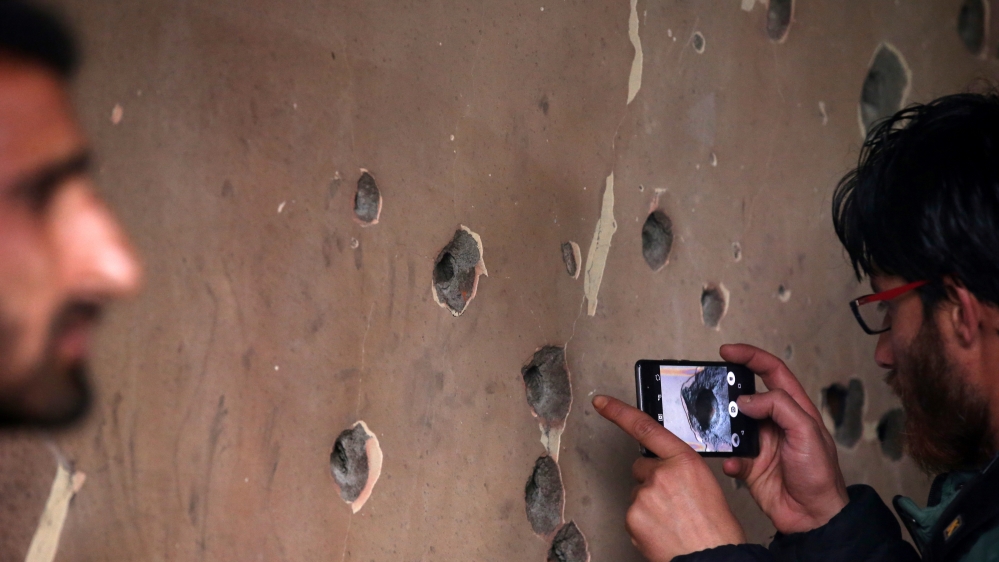 A man uses his mobile phone to take pictures of a bullet-riddled wall of a residential house that was damaged during a gun battle between Zakir Rashid Bhat and Indian security forces