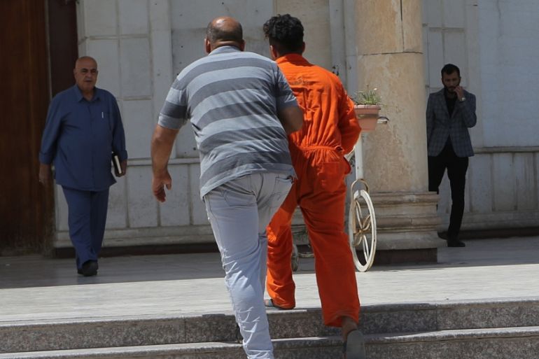 In this Sunday, May 5, 2019 photo, an IS suspect wearing a red prison suit, center right, being led to the Iraqi Criminal Court in Baghdad''s Karkh district, Iraq