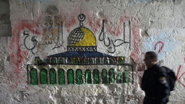 Israeli police officer walks past a mural of the Dome of the Rock in Jerusalem''s Old City