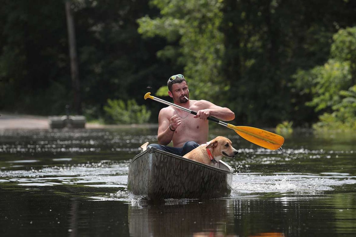 The new method of transport on Highway 61. Ryan Sizemore paddles down the road with his dog Rico, carrying sandbags to his home to hold back the Mississippi River. Barnhart, Missouri.