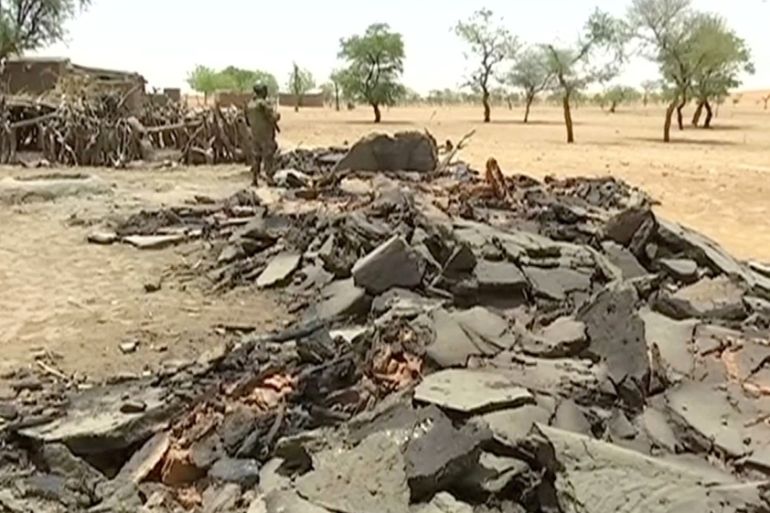 Video grab of a soldier standing near debris from destroyed homes at the site of an ethnic massacre in which gunmen killed dozens of people, in the Dogon village of Sobane Da