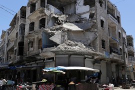 FILE PHOTO: People walk past a damaged building in the city of Idlib