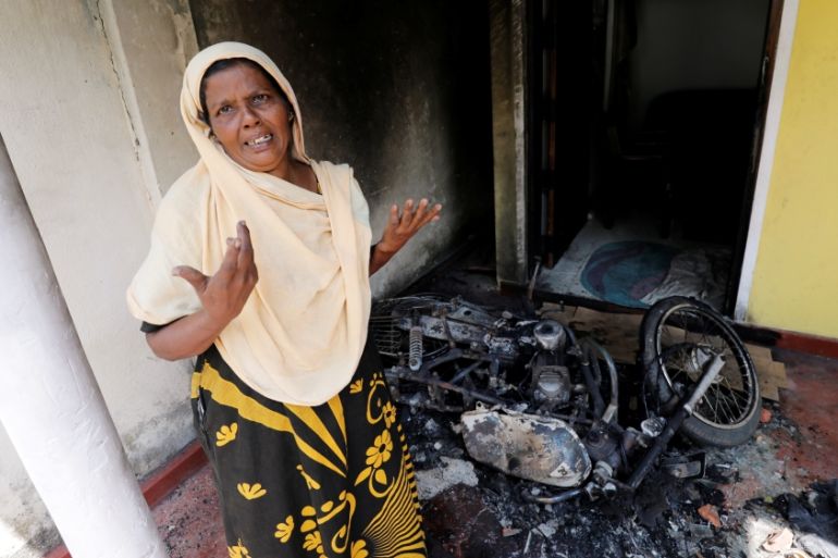 A Muslim woman reacts next to a burnt motorbike and her house after a mob attack in Kottampitiya