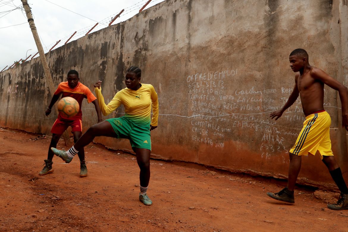 Gaelle Dule Asheri, 17, a soccer player, who is amongst the first wave of girls being trained by professional coaches at the Rails Foot Academy, plays football with her friends outside her house in Ya