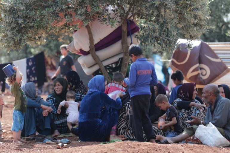 Displaced Syrians sit together in an olive grove in Atmeh town, Idlib province