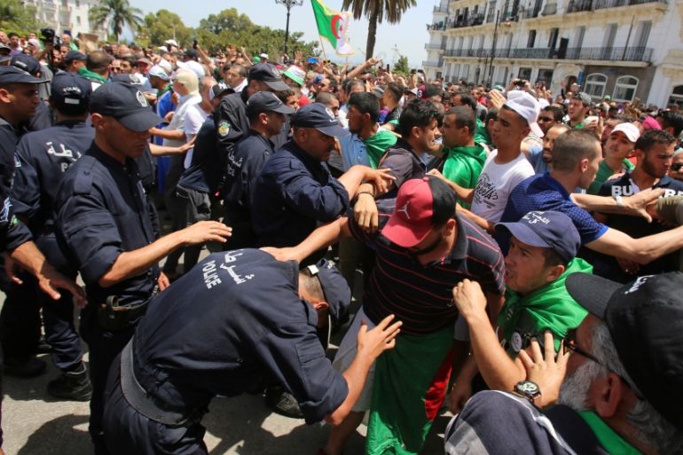 Police officers and demonstrators confront each other during a protest demanding the removal of the ruling elite in Algiers