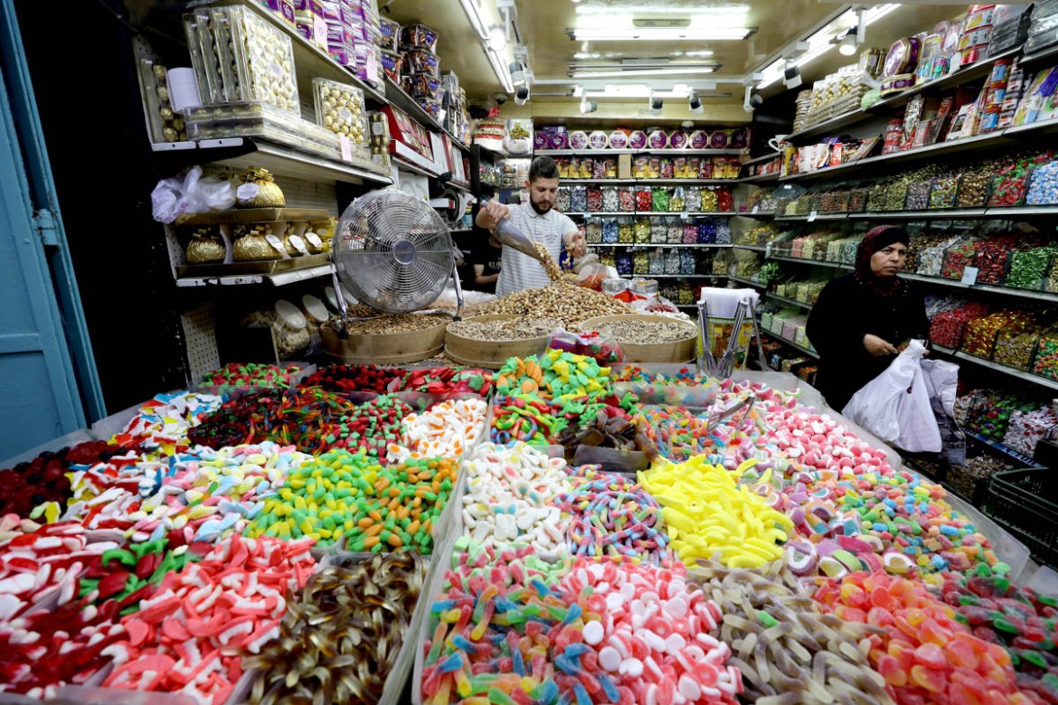 A Palestinian woman stands next to sweets for sale as Palestinians shop ahead of the Muslim holiday of Eid al-Fitr, which marks the end of the holy fasting month of Ramadan, in Jerusalem''s Old City Ju