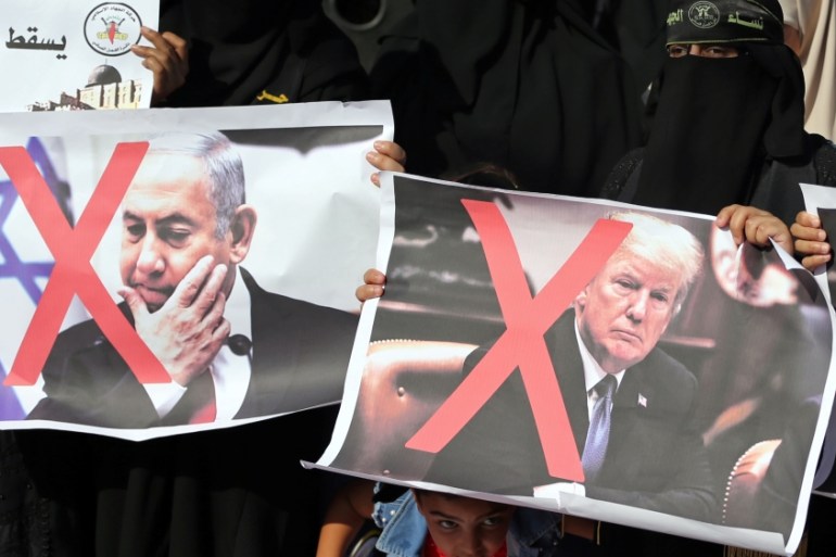 Girl looks on as Palestinian women hold crossed-out posters depicting Trump and Netanyahu during a protest against Bahrain''s workshop for U.S. peace plan, in the southern Gaza Strip