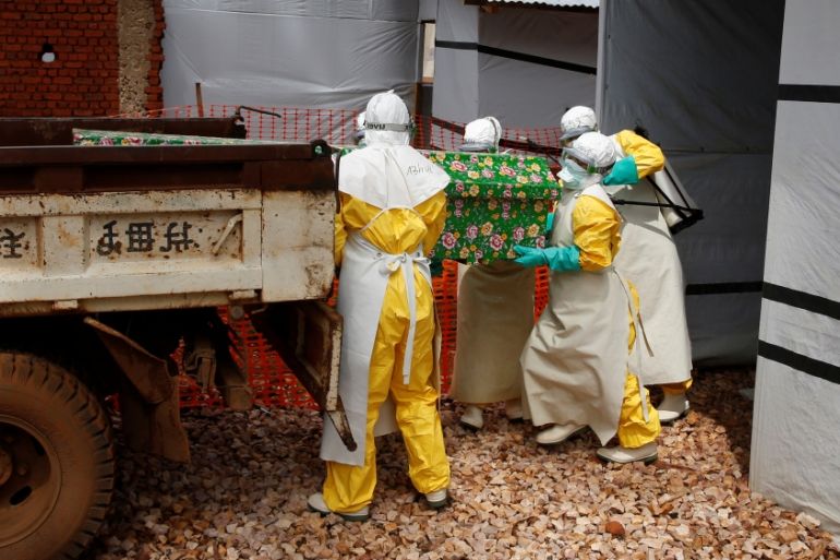 Health workers dressed in Ebola protective suits place a coffin containing the body of an Ebola patient to a truck at an Ebola treatment centre in Butembo