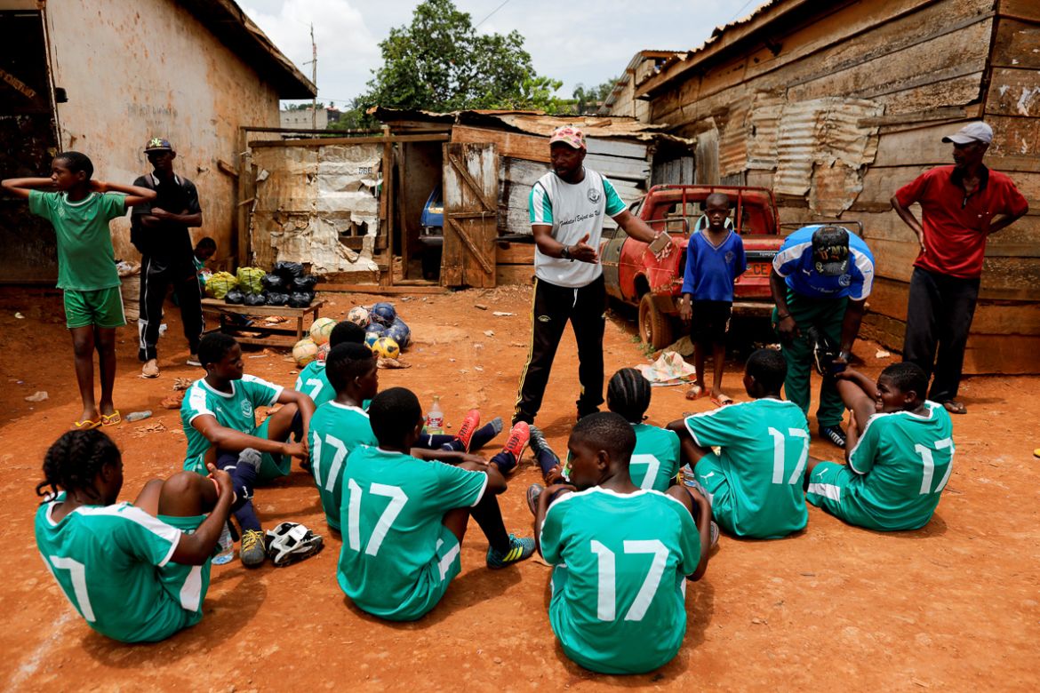 Emmanuel Eteme Biolo, a girls'' U17 team coach, talks with his team during half-time of the match at the Rail Foot Academy field in Yaounde, Cameroon, May 4, 2019. The academy currently trains around 7