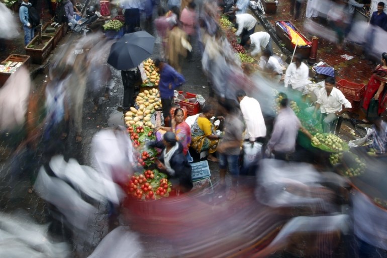 Indians walk past a market area near a train station on World Population Day in Mumbai, India, Thursday, July 11, 2013
