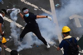 A protester throws back a tear gas during clashes with police outside the government headquarters in Hong Kong on June 12, 2019. - Violent clashes broke out in Hong Kong on June 12 as police tried to