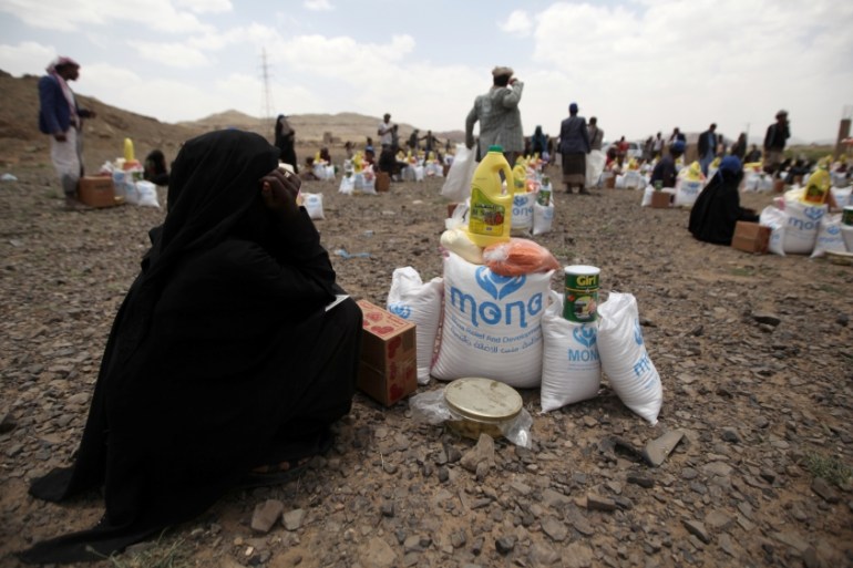 Woman sits next to food aid she received from the local charity, Mona Relief, ahead of the holy month of Ramadan on the outskirts of Sanaa