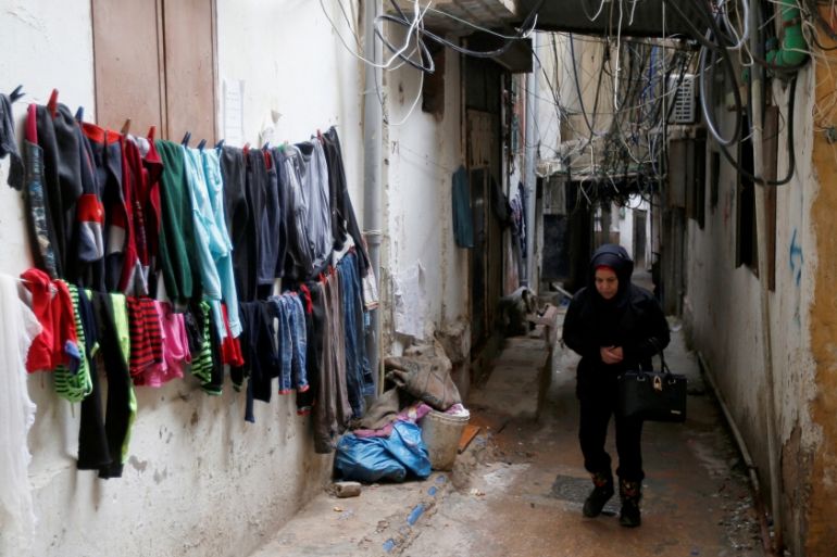 A woman walks past clothes left to dry in Burj al-Barajneh refugee camp in Beirut