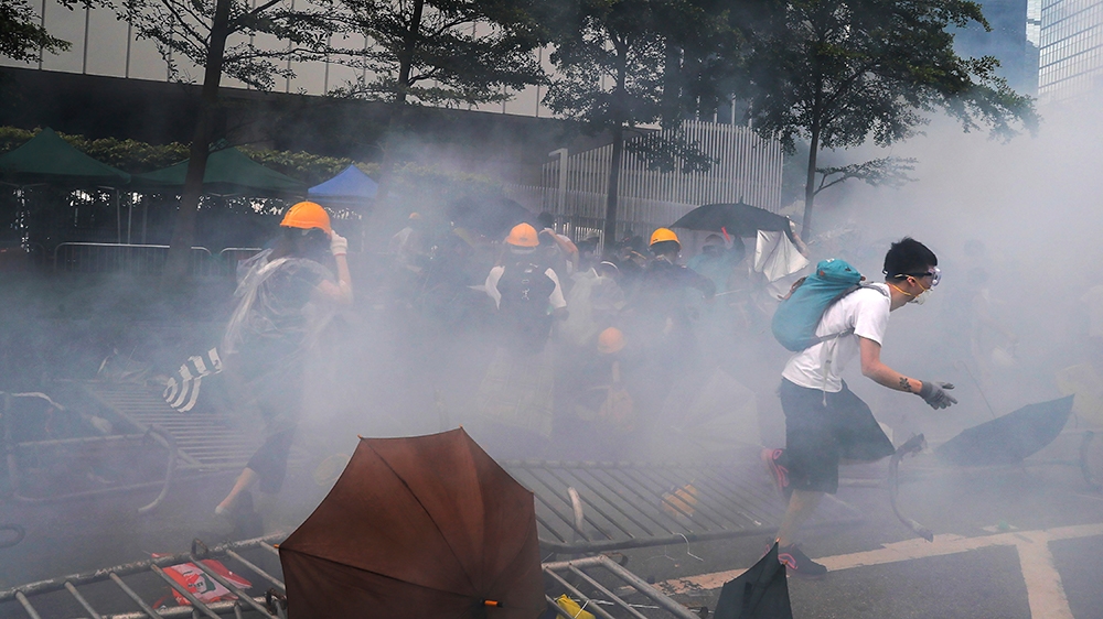 Protesters run away from the tear gas which fired by policemen during a rally outside the Legislative Council in Hong Kong, Wednesday, June 12, 2019. Hong Kong delayed a legislative session on a conte