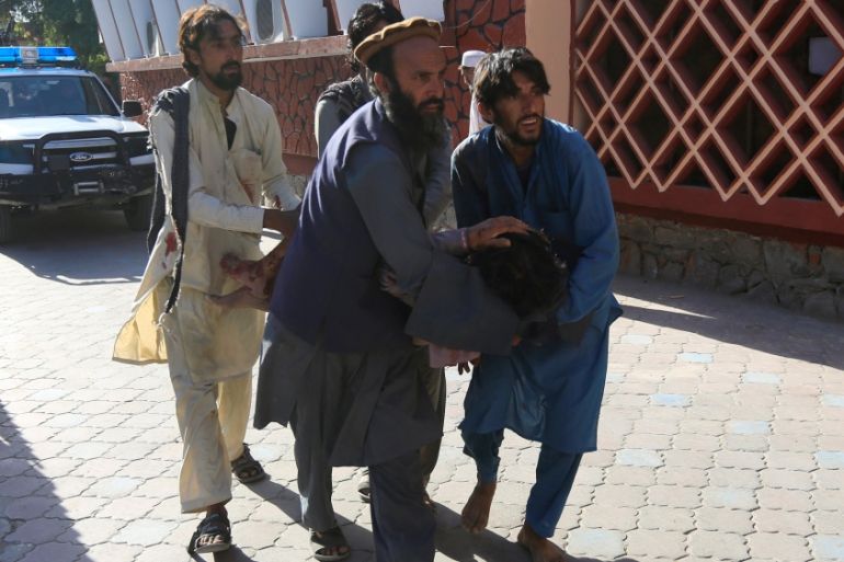 Afghan men carry a wounded person to the hospital after a suicide attack in Jalalabad, Afghanistan