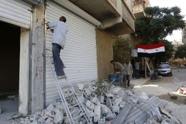 Syrian flags hang from buildings as workers rebuild destroyed stores in Harasta, on the outskirt of the Syrian capital Damascus on July 15, 2018.