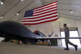 A U.S. Air Force maintainer makes his way into a hangar packed with RQ-4 Global Hawk aircraft, at an Air Force base in Arabian Gulf