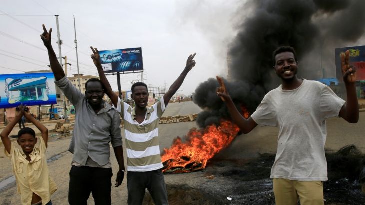 Sudanese protesters gesture near burning tyres used to erect a barricade on a street, demanding that the country''s Transitional Military Council handover power to civilians, in Khartoum