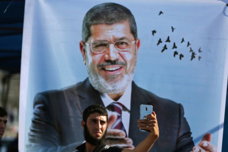 Palestinian man takes a selfie in front of a poster depicting former Egyptian president Mohamed Mursi at a mourning tent for Mursi, in Khan Younis in the southern Gaza Strip