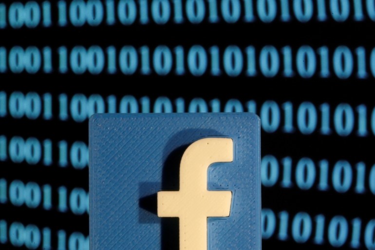 A 3-D printed Facebook logo is seen in front of displayed binary code in this illustration picture
