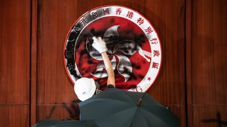 A protester defaces the Hong Kong emblem.