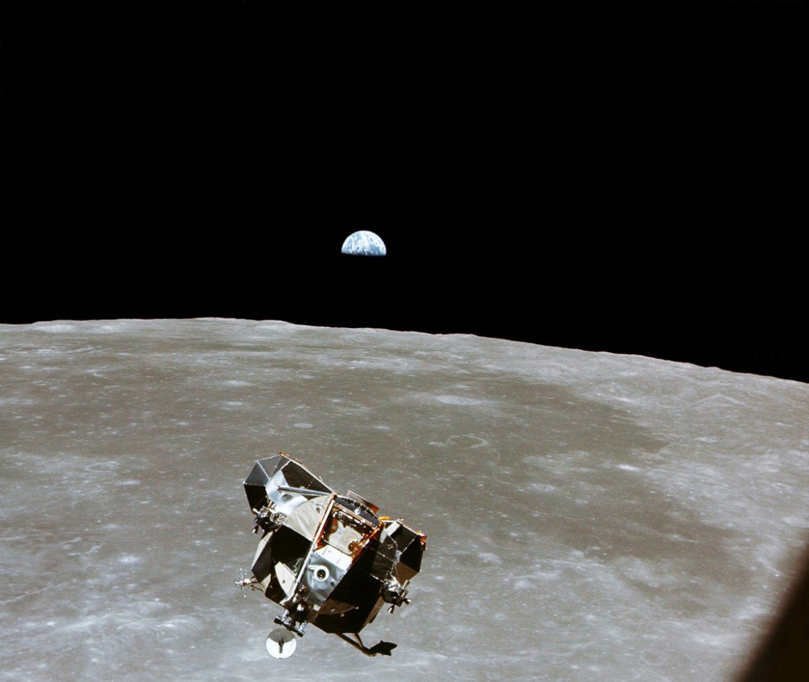 With a half-Earth in the background, the Lunar Module ascent stage with Moon-walking Astronauts Neil Armstrong and Edwin Aldrin Jr approaches for a meeting with the Apollo Command Module manned by Mic