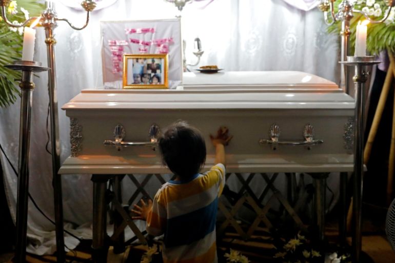 Brother of 3-year-old Ulpina wipes her casket during her wake in Rodriguez, Rizal province