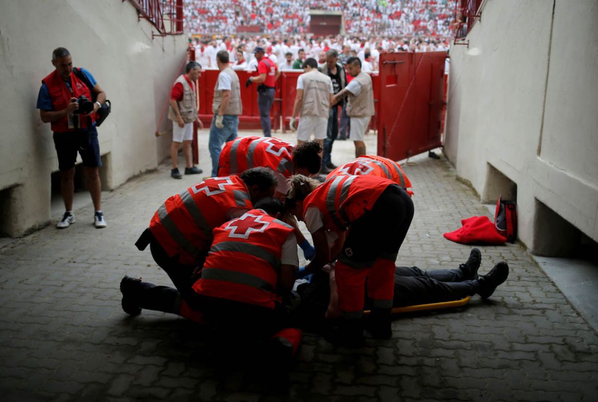 An injured reveller is helped by medical staff during the first running of the bulls at the San Fermin festival in Pamplona, July 7. REUTERS/Jon Nazca