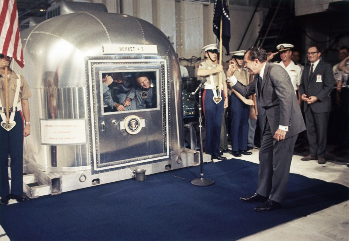 Then-President Richard Nixon gives an ''OK'' sign as he greets Apollo 11 astronauts Neil Armstrong, Michael Collins, and Buzz Aldrin in a quarantine van aboard the USS Hornet on July 24, 1969, after spl
