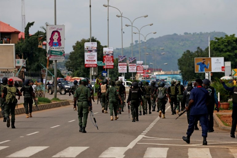 Members of the police head down Banex road during their operation to disperse members of the IMN from a street in Abuja