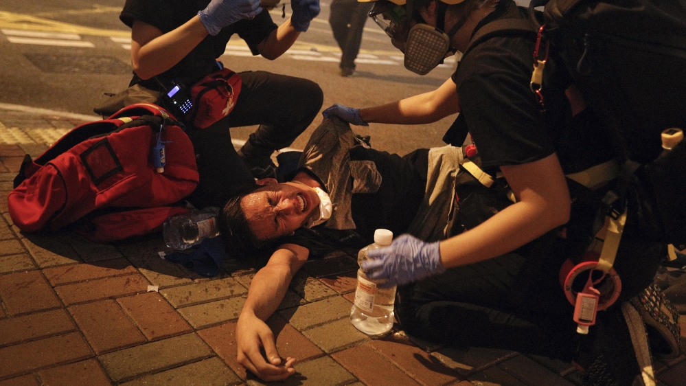 Medical workers help a protester in pain from tear gas fired by policemen on a street in Hong Kong, Sunday, July 21, 2019. Hong Kong police have thrown tear gas canisters at protesters after they refu