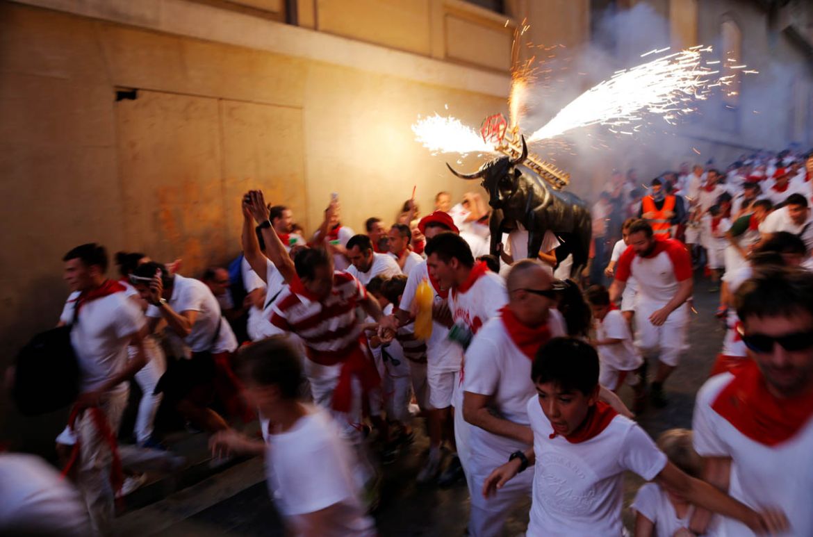 Revellers run next to the Fire Bull, a man carrying a bull figure packed with fireworks, during the San Fermin festival in Pamplona, July 7. REUTERS/Jon Nazca