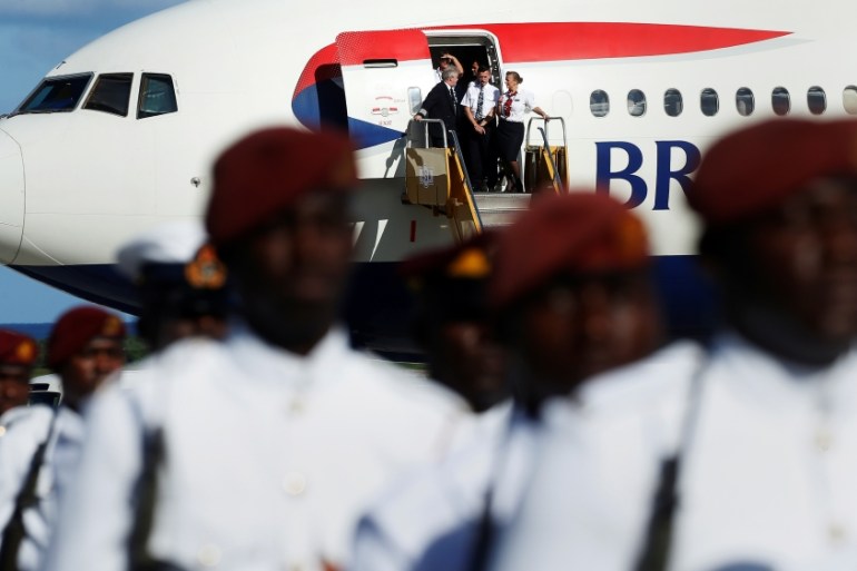 A British Airways flight crew watches as Prince Harry inspects members of Antigua''s military as he arrives at the airport for an official visit in Antigua