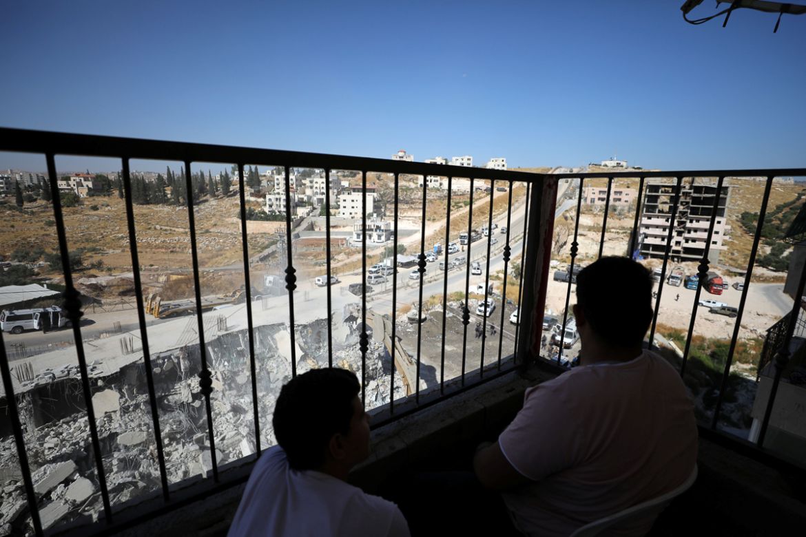 Palestinians watch as an Israeli military bulldozer demolishes a building near a military barrier in Sur Baher, a Palestinian village on the edge of East Jerusalem in an area that Israel captured and