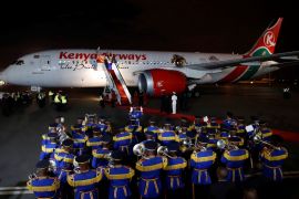 A police band plays as a Kenyan Airways Boeing 787 Dreamliner is seen during a ceremony marking the first non-stop flight, direct to New York City from Nairobi