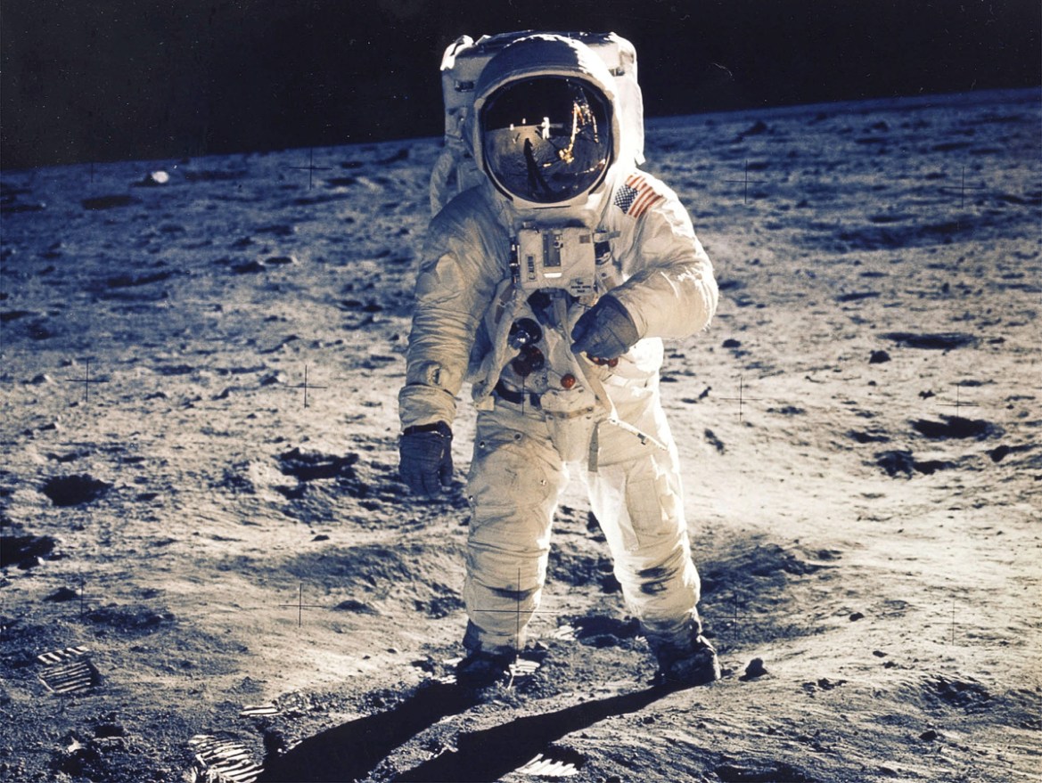 "Working in one-sixth Earth''s gravity, Armstrong and Aldrin gather rocks, set up experiments and plant an American flag stiffened with wires to make it look as if it were waving in the windless vacuum