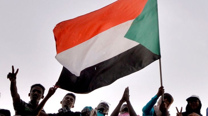 Sudanese demonstrators wave the national flag as they attend a protest rally demanding Sudanese President Omar Al-Bashir to step down
