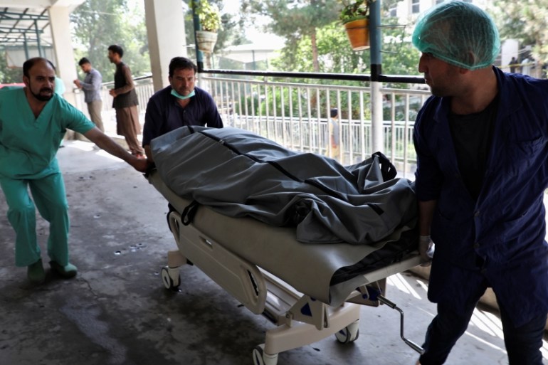 Emergency workers transport the dead body of a victim to the hospital after a blast in Kabul, Afghanistan