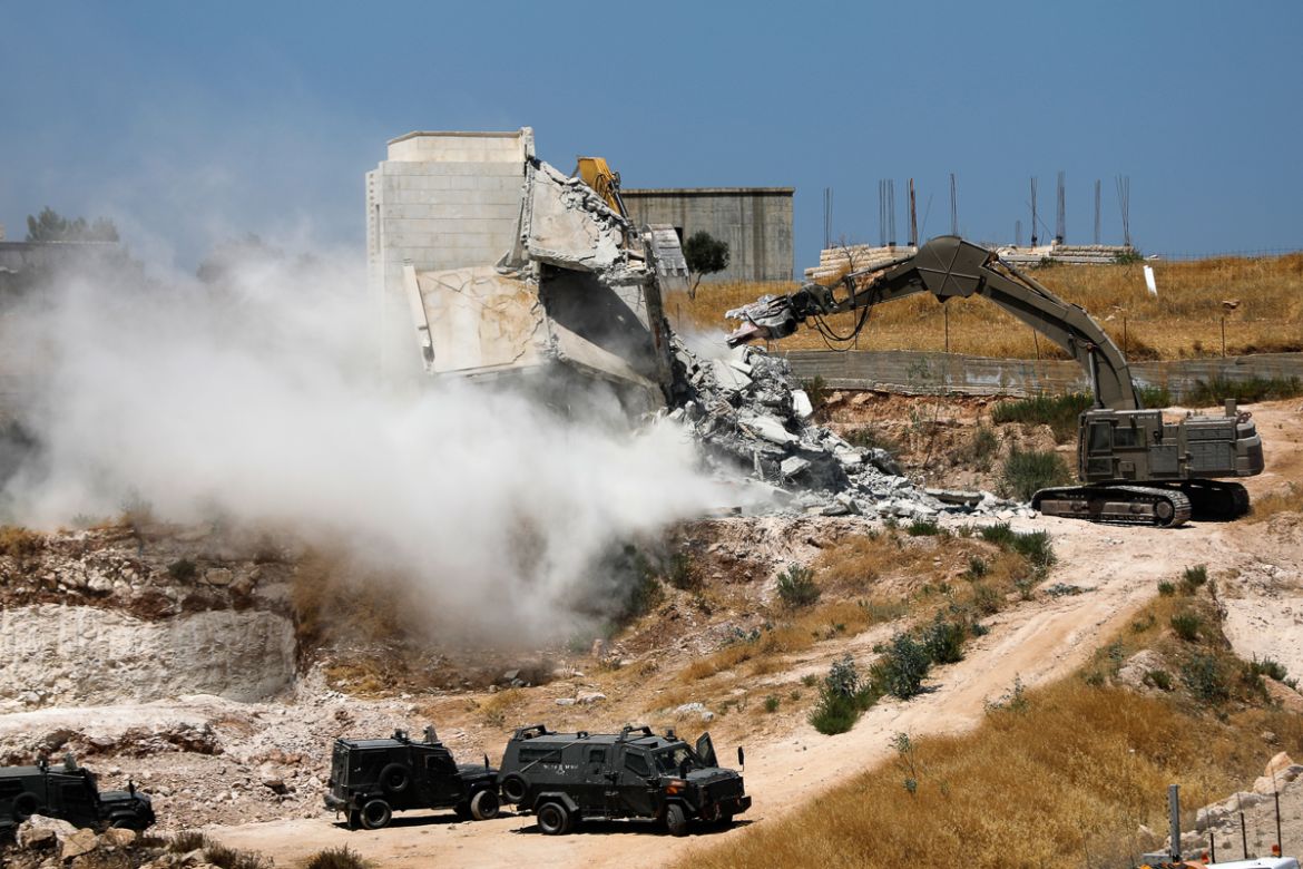 This picture taken from Jerusalem on July 22, 2019 shows Israeli security forces tearing down one of the Palestinian buildings still under construction which have been issued notices to be demolished