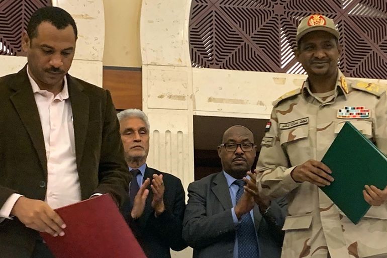 Sudanese deputy chief of the ruling miliary council Mohamed Hamdan Dagalo (R) and protest movement Alliance for Freedom and Changes leader Ahmad al-Rabiah stand after inking an agreement before Africa