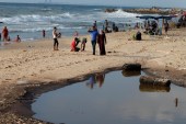 Palestinians walk past a pool of sewage on a beach in the northern Gaza Strip July 13, 2018 [File:Mohammed Salem/Reuters]