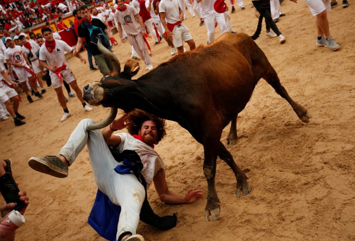 A bull hits a reveller as he falls down in the bull ring after the running of the bulls at the San Fermin festival in Pamplona, Spain, July 9, 2019. REUTERS/Susana Vera