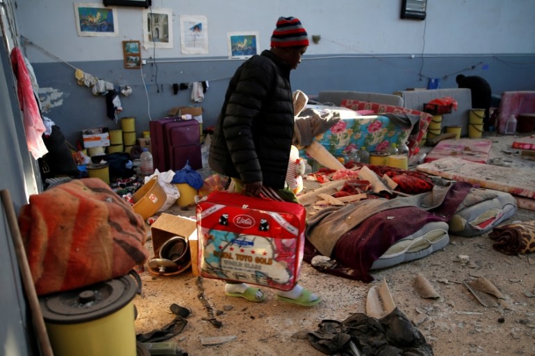 A migrant carries his belongings at a detention centre for mainly African migrants, that was hit by an airstrike in the Tajoura suburb of Tripoli